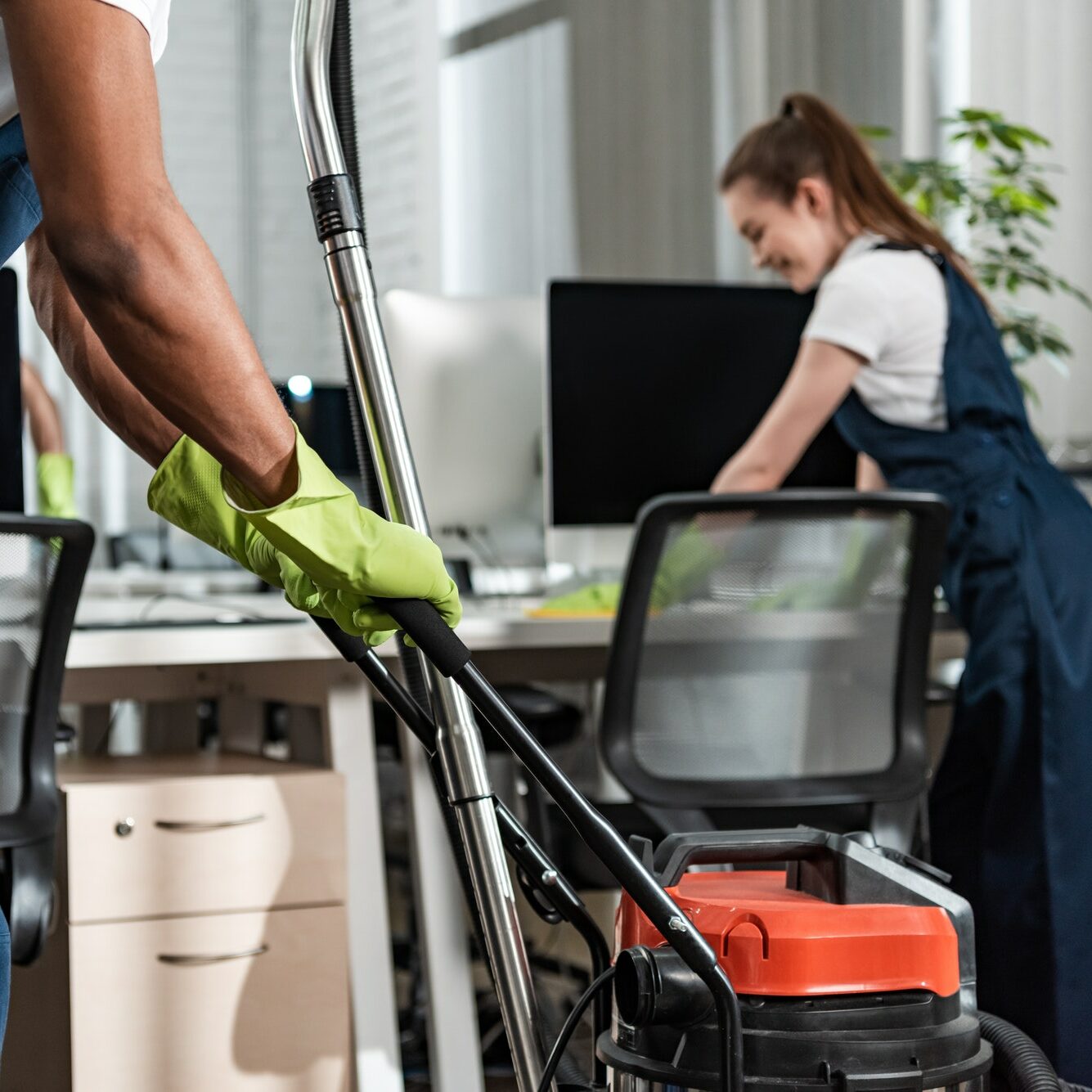 cropped view of african american cleaner moving vacuum cleaner in office